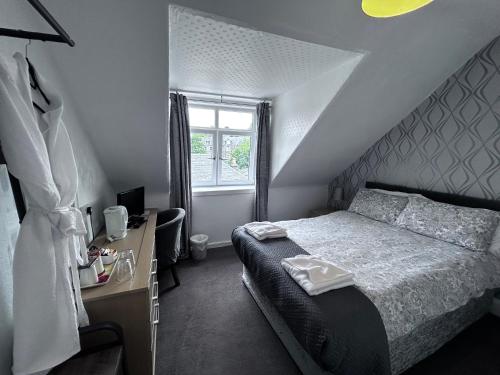 a bedroom with a bed and a desk and a window at Glendale Guesthouse in Oban