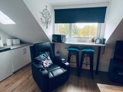 a living room with a chair and a kitchen at Foundry Street Apartment 2 - Dunfermline city centre in Dunfermline