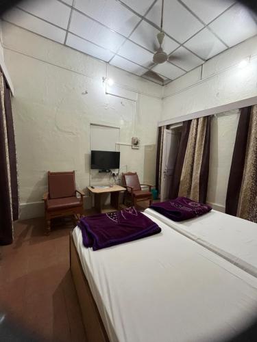 um quarto com uma cama, 2 cadeiras e uma secretária em Hotel Grand Barrack em Khandwa
