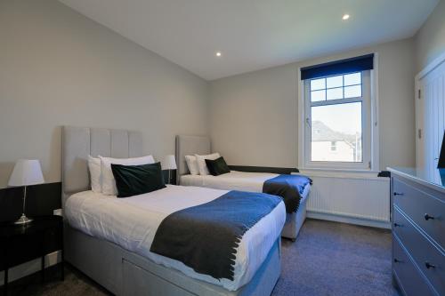 a bedroom with two beds and a window at The White City Apartment in Oban