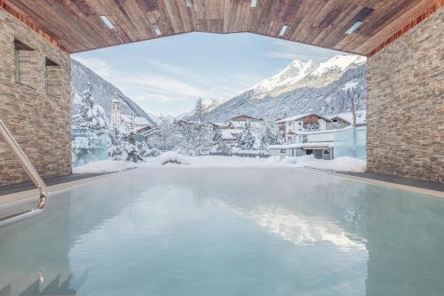 een zwembad met uitzicht op een met sneeuw bedekte berg bij Premium Activehotel Bergkönig in Neustift im Stubaital