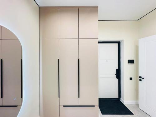 um quarto com armários brancos e uma porta em Shabyt Apartments em Astana
