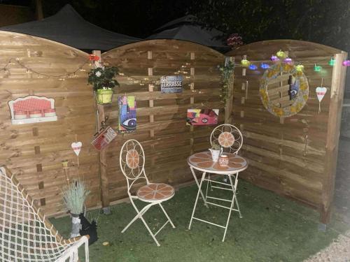a table and two chairs in front of a wooden wall at Comme à la maison in Ducey