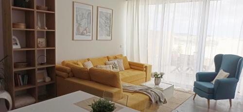 a living room with a yellow couch and a blue chair at Cozy penthouse with Citadel view near to Victoria in Sannat
