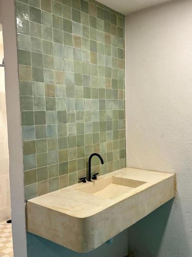 a sink in a bathroom with a green tiled wall at PointBreak Surfhouse in Puerto Escondido