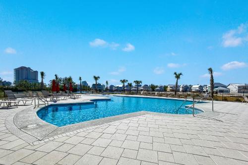 a swimming pool with tables and chairs and palm trees at Waves & Wildlife Getaway at Summer Salt in Orange Beach