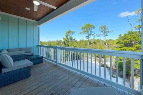 a screened porch with a couch on a deck at Waves & Wildlife Getaway at Summer Salt in Orange Beach