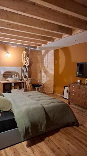 een slaapkamer met een groot bed en een houten plafond bij Le Grenier du Moulin in Darbonnay