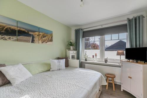 a bedroom with a bed and a television and a window at Ferienhaus Smilla in Meldorf
