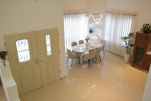 biała jadalnia ze stołem i krzesłami w obiekcie ווילה בנאות לון w mieście Beer Szewa