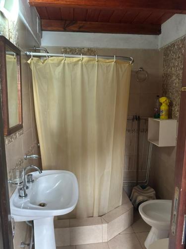 a bathroom with a sink and a shower curtain at La casita de Pablo in Santa Teresita