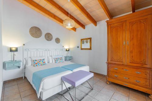 Schlafzimmer mit einem weißen Bett und einem Holzschrank in der Unterkunft Villa Hortet den Joan By home villas 360 in Alcúdia