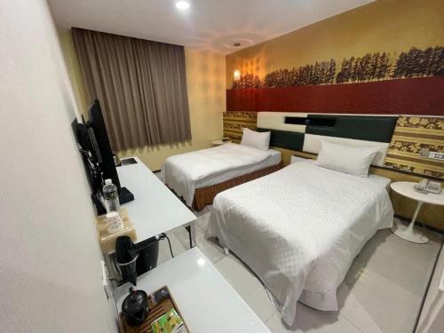 a hotel room with two beds and a television at Two Chung Hotel in Tucheng