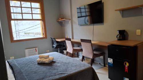 Un dormitorio con una mesa y un osito de peluche en la cama. en Quarto Plus Gonzaga, en Santos