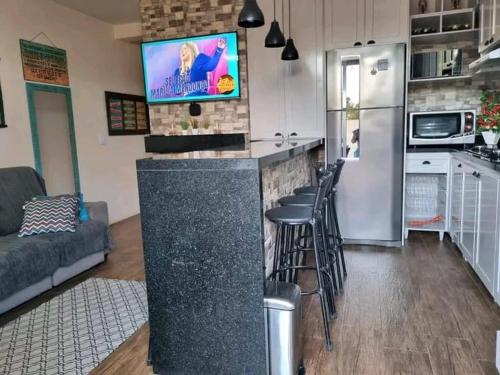 eine Küche mit einer Bar mit Hockern und einem Kühlschrank in der Unterkunft Casa de ferias in Balneário Camboriú