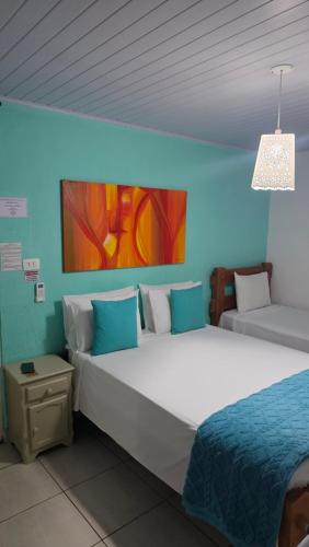 a bedroom with two beds and a blue wall at Pousada jade in Pirenópolis