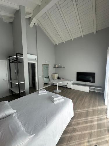 a white bedroom with a large bed and a tv at OFF 32 Suites in Melzo
