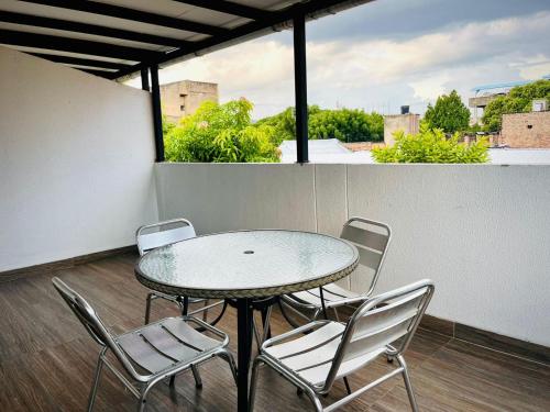 a glass table and chairs on a balcony with a view at Hotel Luxor Cúcuta in Cúcuta