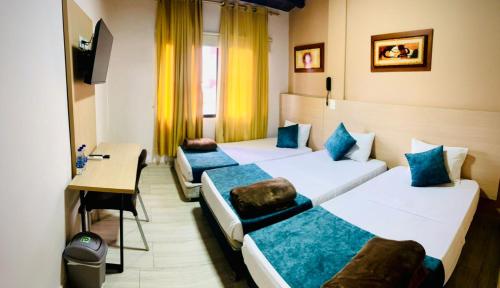 a hotel room with three beds and a desk at Hotel Luxor Cúcuta in Cúcuta