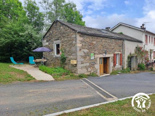 een stenen huis met een tafel en een paraplu bij Rossignol in Le Bez