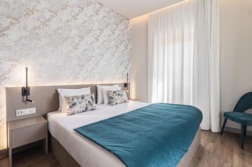 een slaapkamer met een groot bed met een blauwe deken bij Galega Villas in Milharado