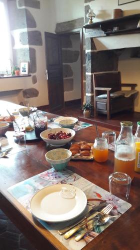 einem Holztisch mit Tellern und Schalen mit Lebensmitteln darauf in der Unterkunft Chambres d'hôtes de Massigoux in Aurillac