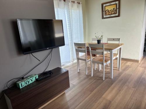 a living room with a table and a flat screen tv at El Vesuvio in San Clemente del Tuyú
