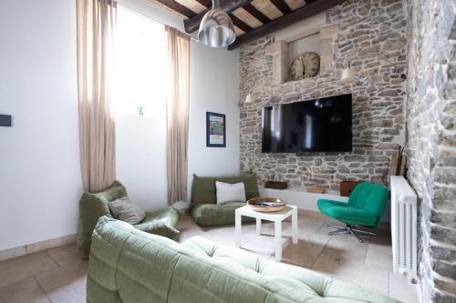 a living room with a green couch and a stone wall at Bardelours 1 Charming house with swimming pool in the heart of the Pic Sa in Saint-Bauzille-de-Montmel