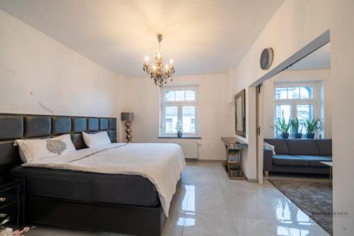 a bedroom with a bed and a couch and a chandelier at Villa am Staderhof in Leichlingen