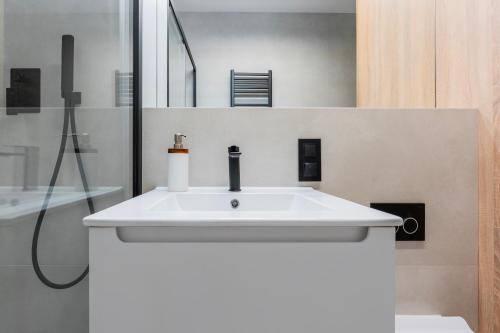 a bathroom with a white sink and a shower at K26UrbanNest in Wrocław