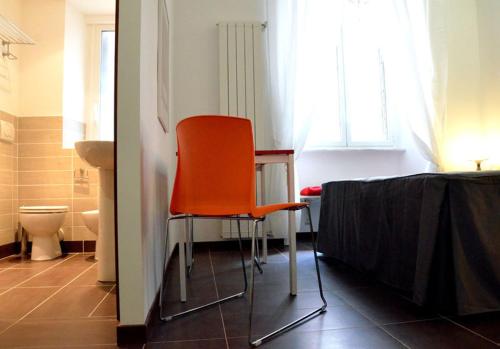 a orange chair in a room with a bathroom at Maison Colosseo (Via dei Querceti 24) in Rome