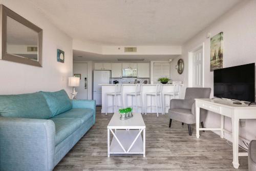 a living room with a blue couch and a kitchen at Tortuga Suite at Sunrise Suites Resort - Heated Pool, Hot Tub & Free Parking in Key West