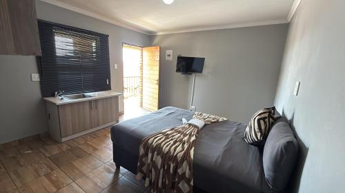 ein Schlafzimmer mit einem Bett und einem Waschbecken in der Unterkunft Gnostes Lodge Vosloorus in Vosloorus