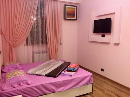 a bedroom with a purple bed with a tv on the wall at Elegant 3 bedroom apartment in center, next to Reppublic Square in Yerevan