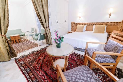 ケルアンにあるDar Dhiafa Paul Klee Kairouanのベッドとテーブルと椅子のある寝室