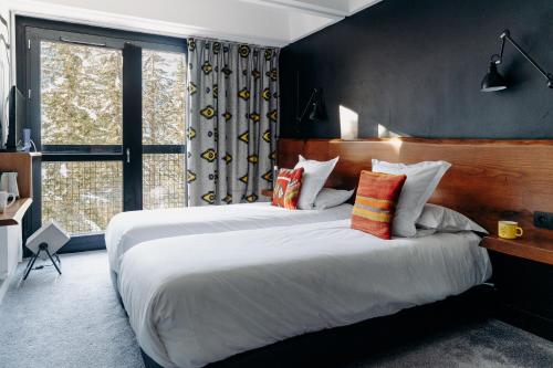 Un dormitorio con una cama grande y una ventana grande en Totem, Friendly Hotel & Spa, en Flaine