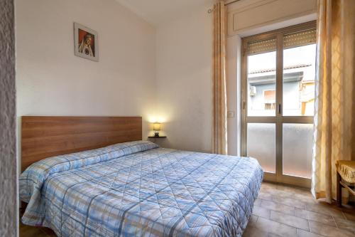 a bedroom with a bed with a blue comforter and a window at Veranda Vista Mare Isola Rossa in Isola Rossa