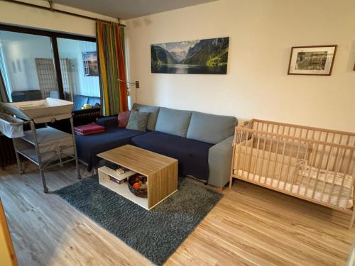 a living room with a blue couch and a crib at Ferienwohnung Sunnabichi in Wertach