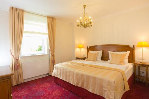 a bedroom with a bed with a chandelier and a window at Hotel Erbprinzenpalais in Wernigerode