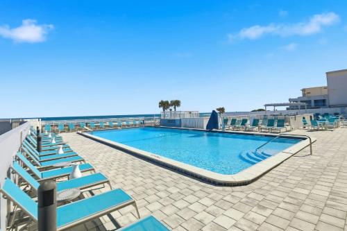 piscina con sedie a sdraio blu e oceano di The Maverick Resort - Ormond Beach a Ormond Beach