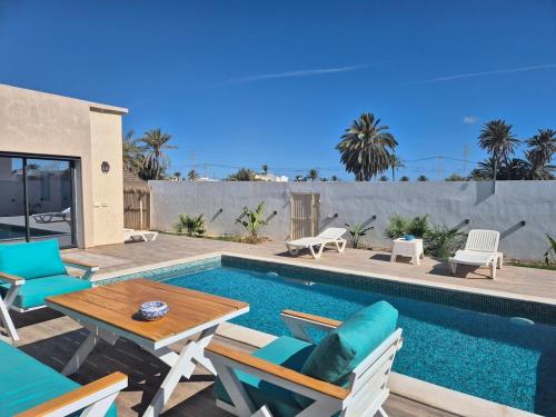 a patio with a table and chairs next to a swimming pool at Villa Midoun in Midoun