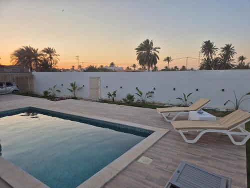 a swimming pool with two chairs next to a fence at Villa Midoun in Midoun