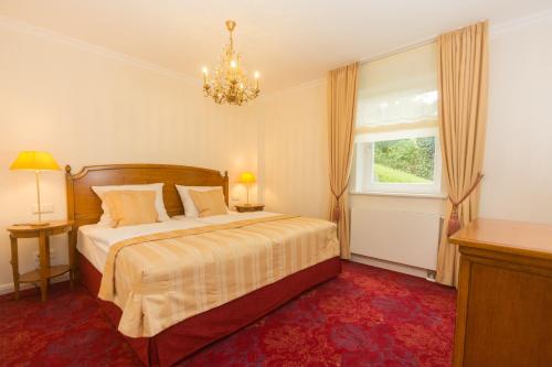 a bedroom with a bed with a chandelier and a window at Hotel Erbprinzenpalais in Wernigerode