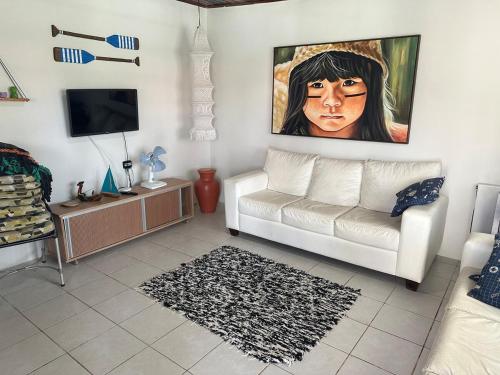 ein Wohnzimmer mit einer weißen Couch und einem Gemälde an der Wand in der Unterkunft Casa de Férias no Sôssego in Itamaracá