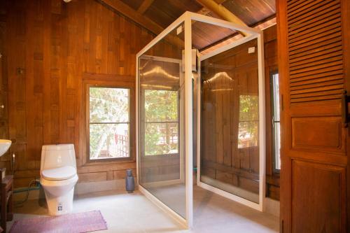 a bathroom with a toilet in a wooden house at Teak House Homestay I in Ban Thung Satong