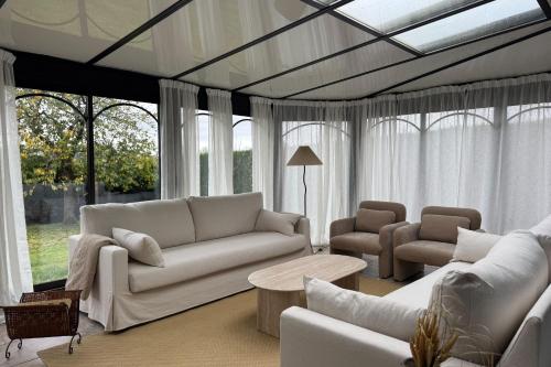 ein Wohnzimmer mit weißen Möbeln und Fenstern in der Unterkunft Harmony Homes Le Cottage Bleu - Indoor Pool Sauna & Spa in Le Planquay