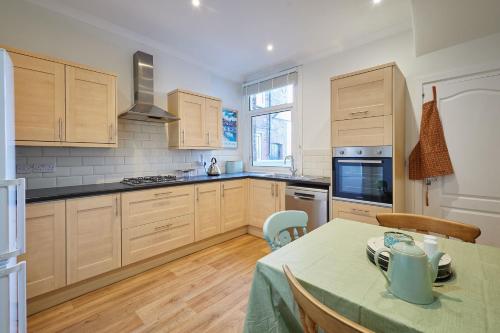 eine Küche mit Holzschränken und einem Tisch mit einem grünen Tischtuch in der Unterkunft Host & Stay - Prospect Retreat in Knaresborough