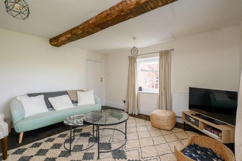 a living room with a couch and a tv at Historic Riverside House - Village, River Walks & Easy York Access in Cawood