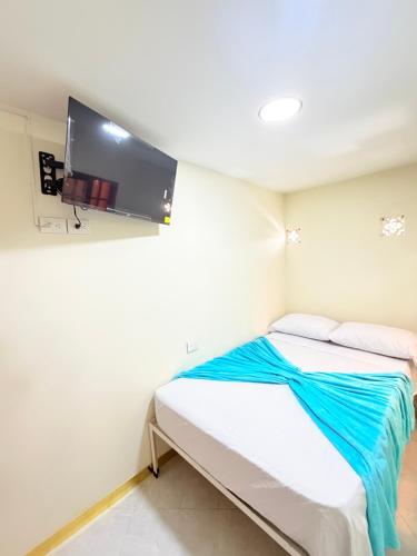 a small room with a bed with a tv on the wall at Hotel San Vicente in Medellín