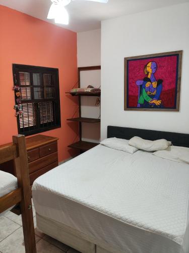 a bedroom with a bed and a painting on the wall at Praia litoral norte SP 70 m praia in Caraguatatuba